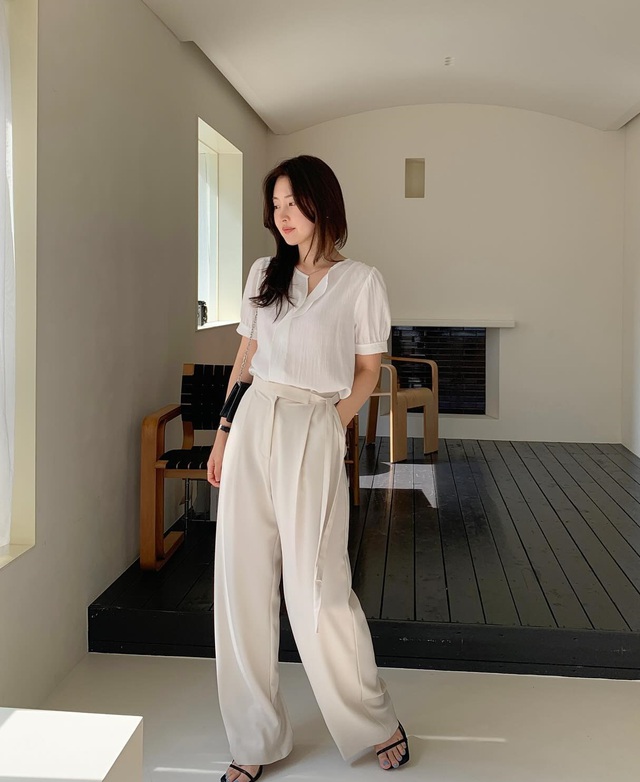 Áo blouse trắng tay bồng và quần âu màu trắng, đi sandal cao gót quai mảnh sang chảnh
