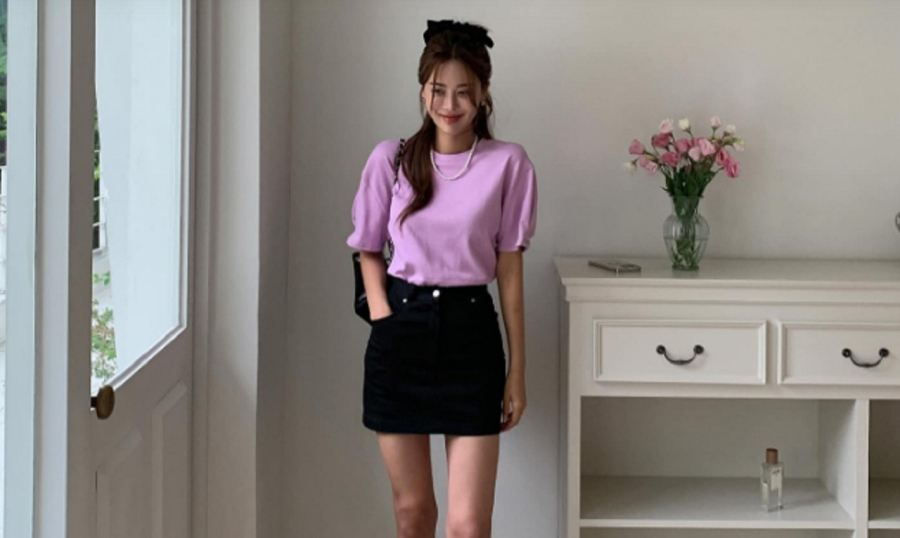 Áo màu tím pastel kết hợp cùng chân váy ngắn, sandal và túi xách cùng tông màu đen.