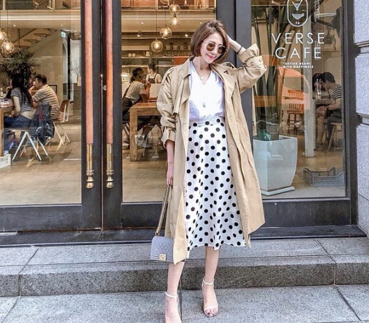 Các nàng hoàn toàn có thể tận dụng chiếc áo blouse cùng chân váy chấm bi của mùa hè để cùng với trench coat tạo nên set đồ nữ tính và trang nhã như quý cô này.  