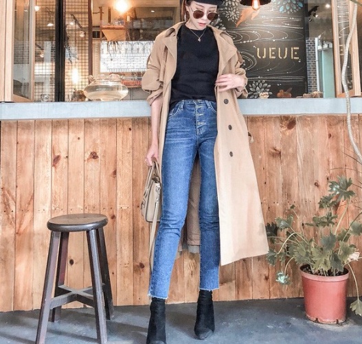 Diện bên trong áo trench coat một chiếc áo phông đen, quần jeans cạp cao thêm đôi boots cùng màu áo
