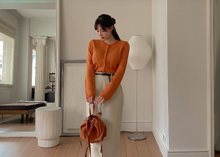 Công thức áo cardigan màu cam, chân váy suông trắng kem và boots cao cổ ghi điểm ở sự nữ tính, thanh lịch.