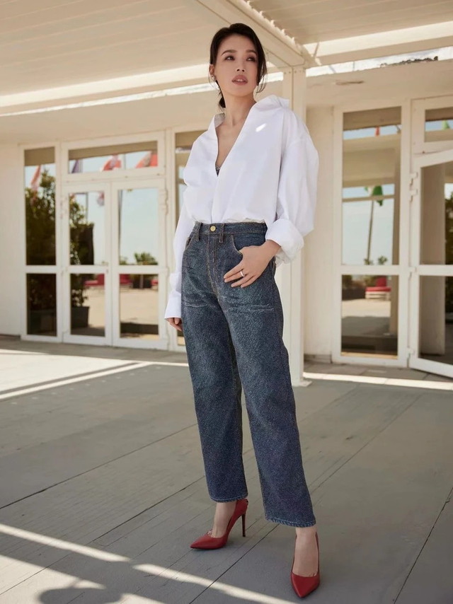 Công thức áo sơ mi trắng và quần jeans ống đứng trở nên nữ tính, nổi bật hơn nhờ đôi giày cao gót màu đỏ.
