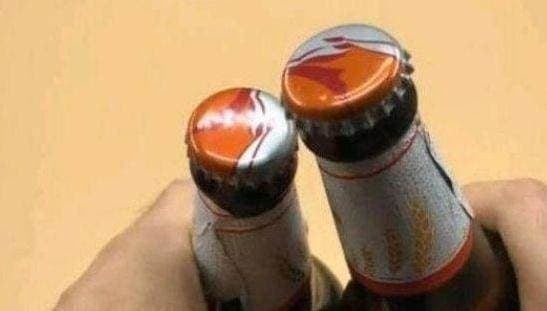 Nếu không có dụng cụ mở bia, bạn có thể tận dụng hai chai bia để làm điều đó.