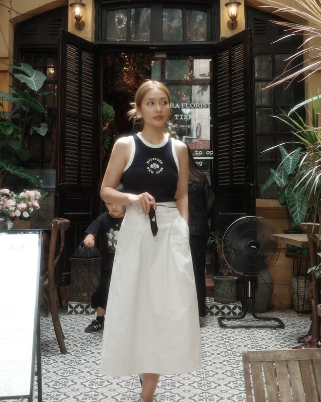 Khả Ngân chứng minh rằng áo tank top không chỉ năng động mà còn có thể rất dịu dàng khi phối cùng chân váy trắng. 