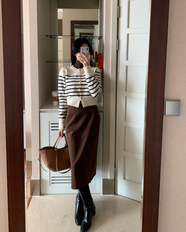 Kết hợp áo cổ lọ bên trong, khoác ngoài áo cardigan kẻ ngang cùng chân váy suông sẽ mang đến một diện mạo nhẹ nhàng và sang trọng. 