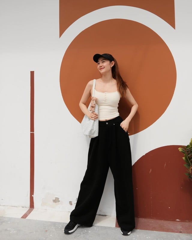 Sự đơn giản nhưng đầy tinh tế thể hiện qua outfit gồm áo hai dây trắng và quần ống suông đen.