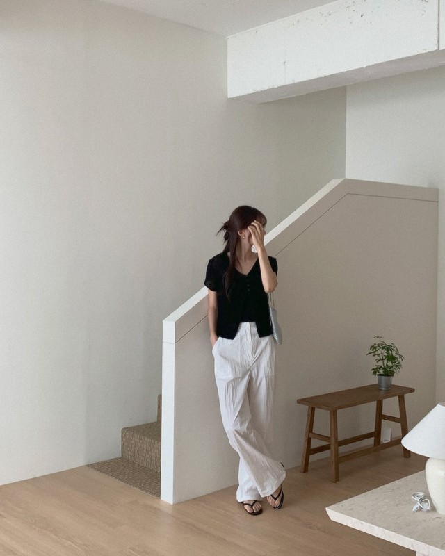 Nếu muốn một lựa chọn nhẹ nhàng cho cuối tuần, hãy thử phối áo len cộc tay màu đen với quần vải trắng dáng suông.