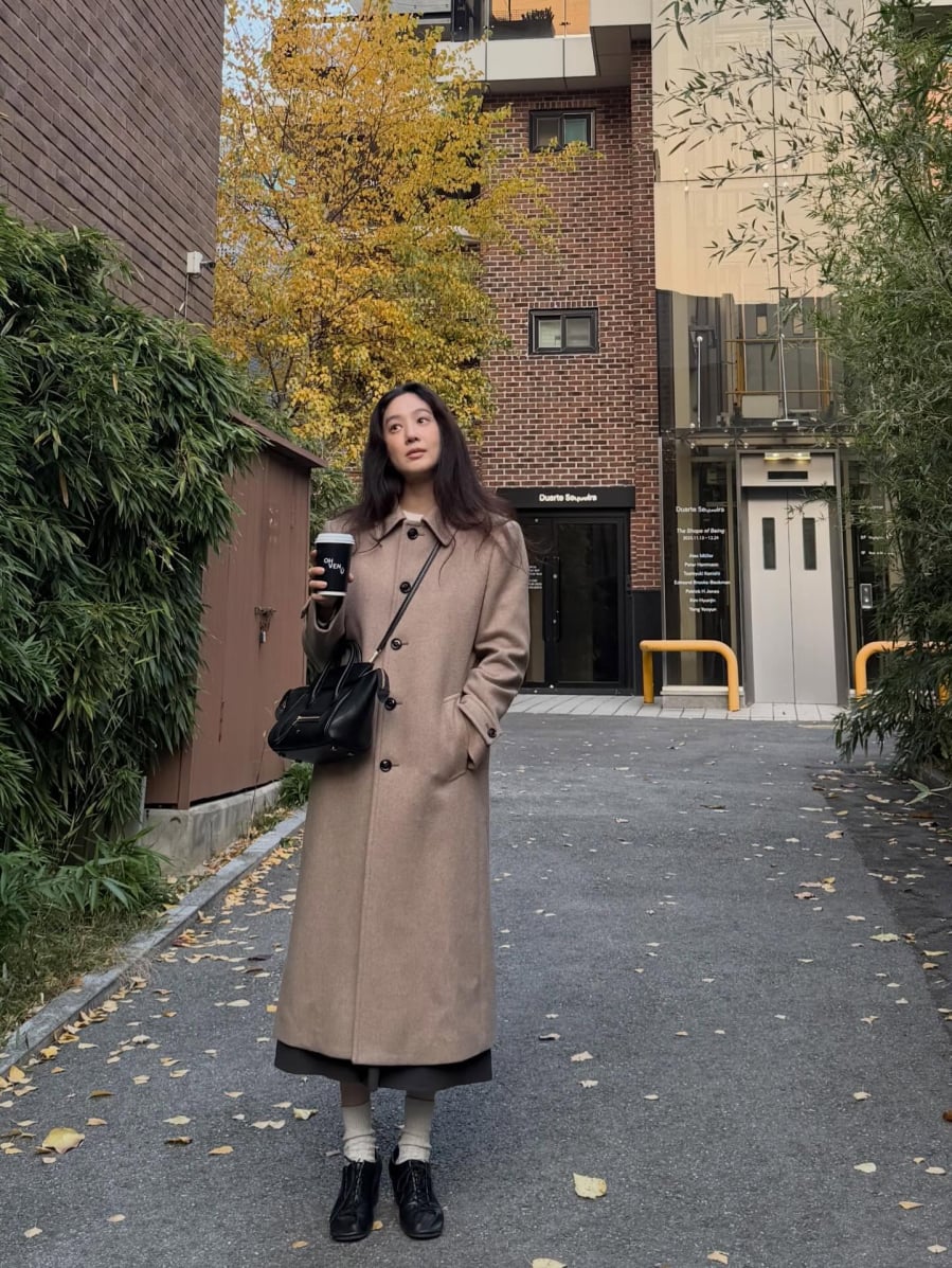 Jung Ryeo Won chọn mẫu áo dạ màu be đơn giản, kết hợp tinh tế cùng áo trắng và chân váy dài để tạo nên vẻ ngoài thanh lịch và mềm mại. 