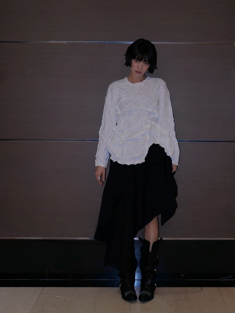 Một trong những bản phối được đánh giá cao là sự kết hợp giữa áo blouse trắng có hiệu ứng xếp nếp cùng chân váy bất đối xứng màu đen.
