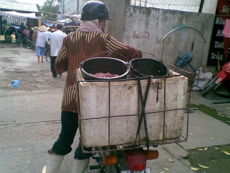Một người thu mua nội tạng lợn mang ra chợ bán lại cho người bán lẻ