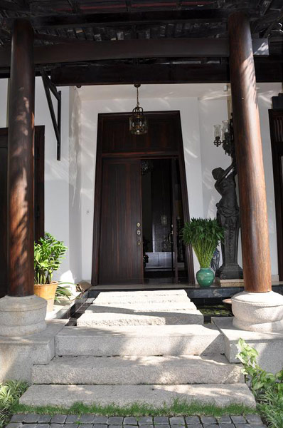 Lối vào với bậc đá, cửa gỗ và cột trụ được làm từ những cây gỗ lớn, lâu năm
