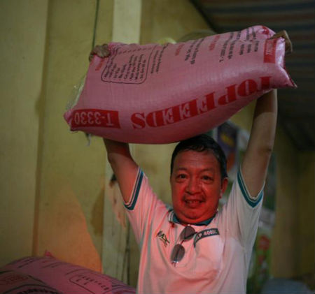 Ông Nhiệm vác bao gạo đi băng băng.