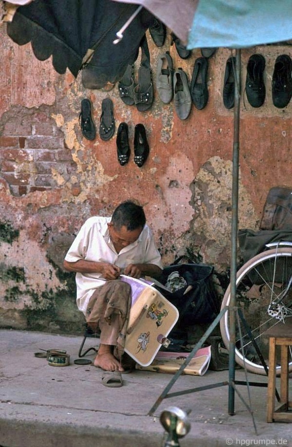 Thợ sửa đồ da tại một góc vỉa hè.