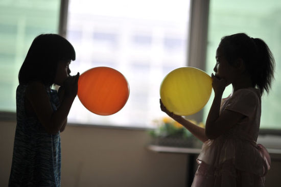 Hai bé gái thổi bóng bay để trang trí cho buổi biểu diễn văn nghệ.