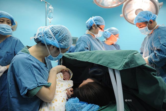 Trong khi các bác sỹ tiến hành khâu lại dạ con và bụng Guo Jia, cô đồng thời cũng được y tá cho xem mặt con.