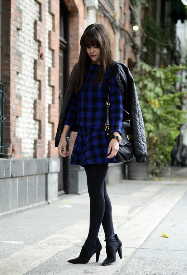 Áo khoác da diện ngoài váy kẻ tartan xanh cobalt và đen mang đến vẻ bí ẩn cho bạn gái.