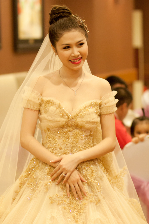 Thủy Anh, vợ Đăng Khôi, nằm trong top những cô dâu diện váy nghìn đô. Bộ đầm trễ vai màu vàng ánh kim nhạt mang đến cho cô dâu một con vẻ đẹp đằm thắm rạng ngời.