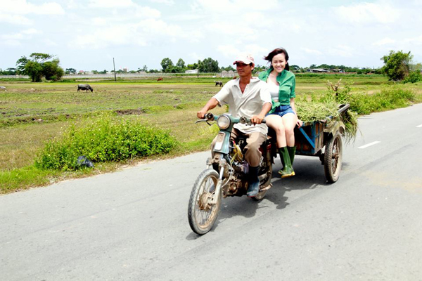 Bà Tưng tươi cười trên xe chở lúa.
