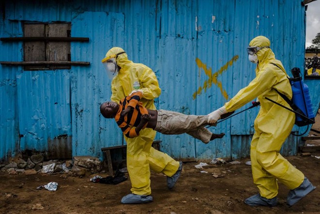 Nhân viên y tế di chuyển một đứa trẻ nhiễm Ebola tại Monrovia, Liberia hôm 5/9. Phóng viên Daniel Berehulak có mặt tại hiện trường cho biết cậu bé 8 tuổi James Dorbor nằm hấp hối dưới nền nhà.