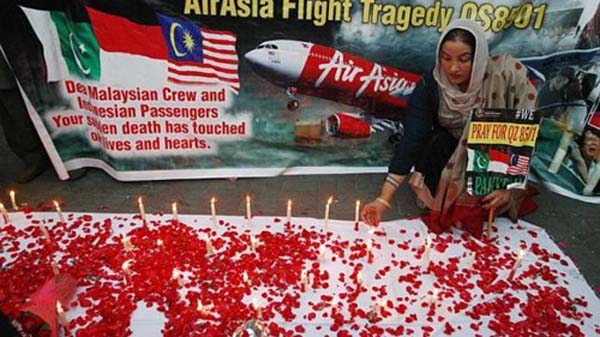 Một thành viên của Hội đồng Luật sư Pakistan cầm biểu ngữ và thắp nến cầu nguyện cho các hành khách trên chuyến bay QZ8501 tại thành phố Lahore hôm 2/1.