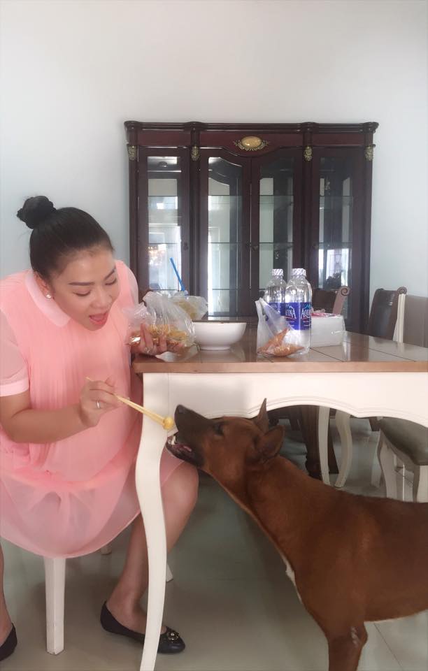 Thu Minh khắc hẳn với vẻ lộng lẫy trên sân khấu, giản dị khi ở nhà: 'Măm măm bánh tráng trộn với Chế Bầu nhé. Ăn xong rồi mới đút cho em Chó nhé...kẻo Cả Nhà nói Tớ mất vệ sinh hihi.'