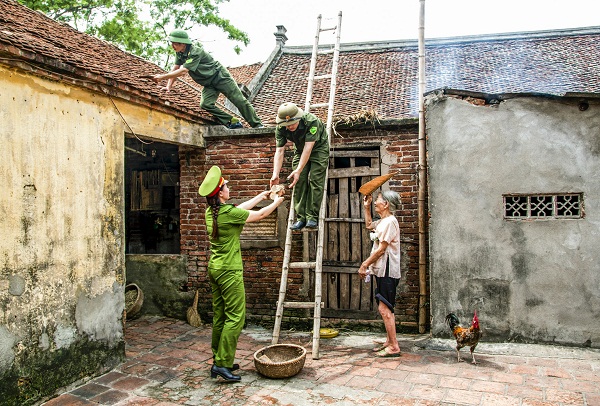 Các chiến sĩ công an nhân dân giúp dân đảo ngói sau mưa.
