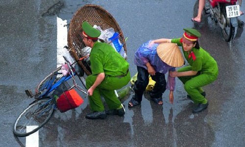 Hai chiến sĩ công an trẻ tuổi bất chấp trời mưa, ướt áo dừng lại giúp đỡ một cụ già đi đường chẳng may đổ chiếc xe đạp cùng với vật dụng mưu sinh.