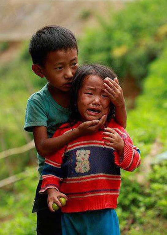Một cậu bé người dân tộc thiểu số đang cố gắng dỗ dành cô em gái bé nhỏ của mình.