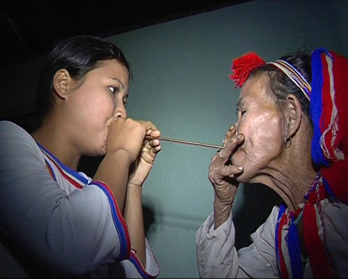 Bà không những yêu thương cháu, bà còn dạy cháu những điều hay, điều tốt. Trong ảnh là bà Hồ Thị Bảy, ở thôn Trà Nga, xã Trà Phong, huyện Tây Trà (Quảng Ngãi) đang dạy cháu mình chơi kèn Amap, một loại đạo cụ dân tộc.