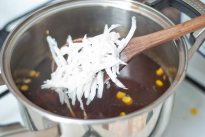 Thêm ngô đã luộc chín và dừa nạo vào nồi.