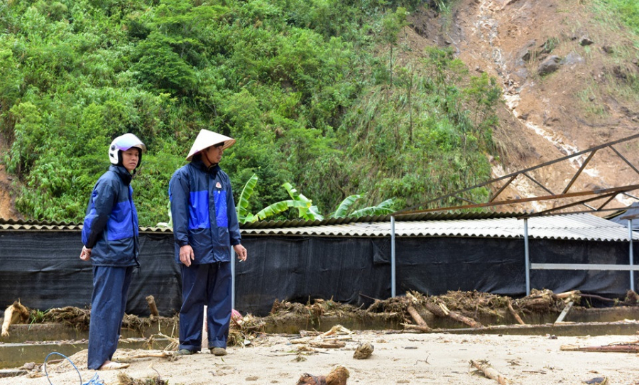 Anh Long (đội nón) đứng thẫn thờ nhìn trang trại cá và nhà mình thành đống đổ nát
