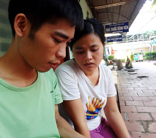 Vợ chồng anh Chiến, chị Dương xem ảnh con mỗi lúc không được vào trong nhìn con
