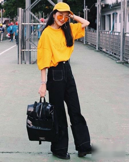 Set đồ áo thun vàng cùng quần jeans, mũ lưỡi trai và balô mang lại dáng vẻ thanh lịch, cổ điển cho người mặc.    