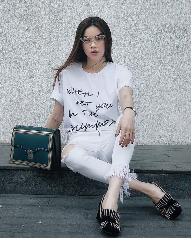 Hồ Ngọc Hà ''hạ nhiệt'' ngày hè với set đồ tuyền trắng, mix ăn ý áo phông của nhà thiết kế Hà Nhật Tiến và quần xé gấu tiệp màu. Đôi giày nạm đá lấp lánh, túi xách porfolio của Gucci, cộng thêm mắt kính cực ''cool'' trở thành bộ 3 lý tưởng giúp người đẹp tăng vẻ thời thượng.  