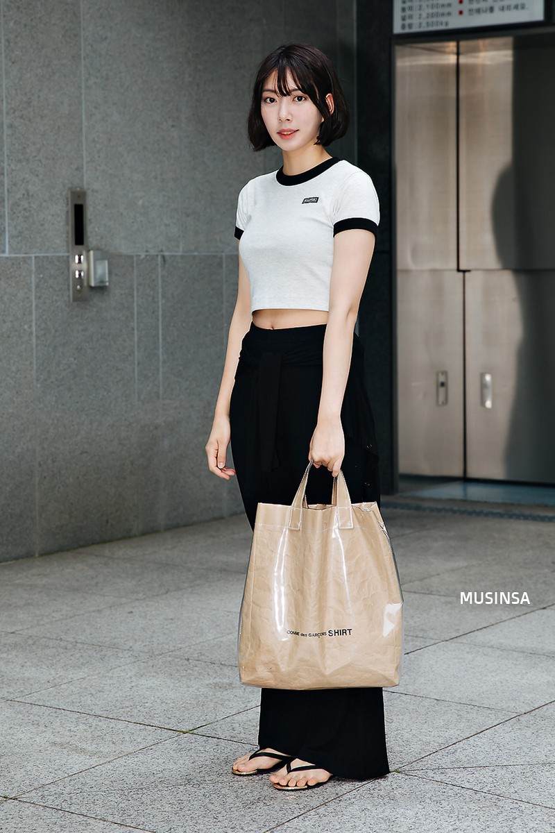Hai điểm nhấn thú vị nhất trong street style của cô nàng này chính là chiếc túi tote plastic kết hợp giấy vô cùng hay ho và đôi dép xỏ ngón casual mà phóng khoáng.    