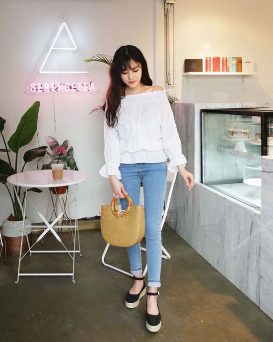 Set đồ dễ dàng mặc đi muôn nơi gồm áo trễ vai tông trắng, quần jeans ôm, giầy đế xuồng và túi xách tay chất liệu thiên nhiên.