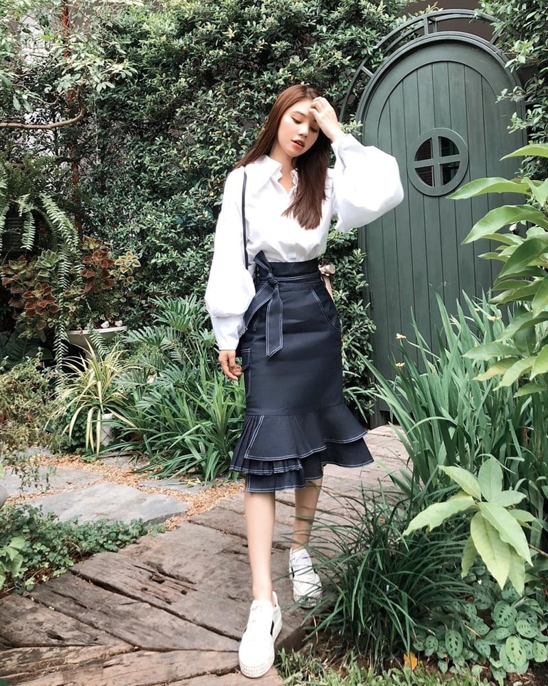 Cùng với áo khoác denim, sơ mi trắng cũng là một trong những tiêu điểm của tuần qua. Lựa chọn thiết kế tay phồng tuyền trắng, Jolie Nguyễn mix áo với chân váy loa kèn tôn dáng, chấm phá bằng đôi giày thể thao Gucci.    