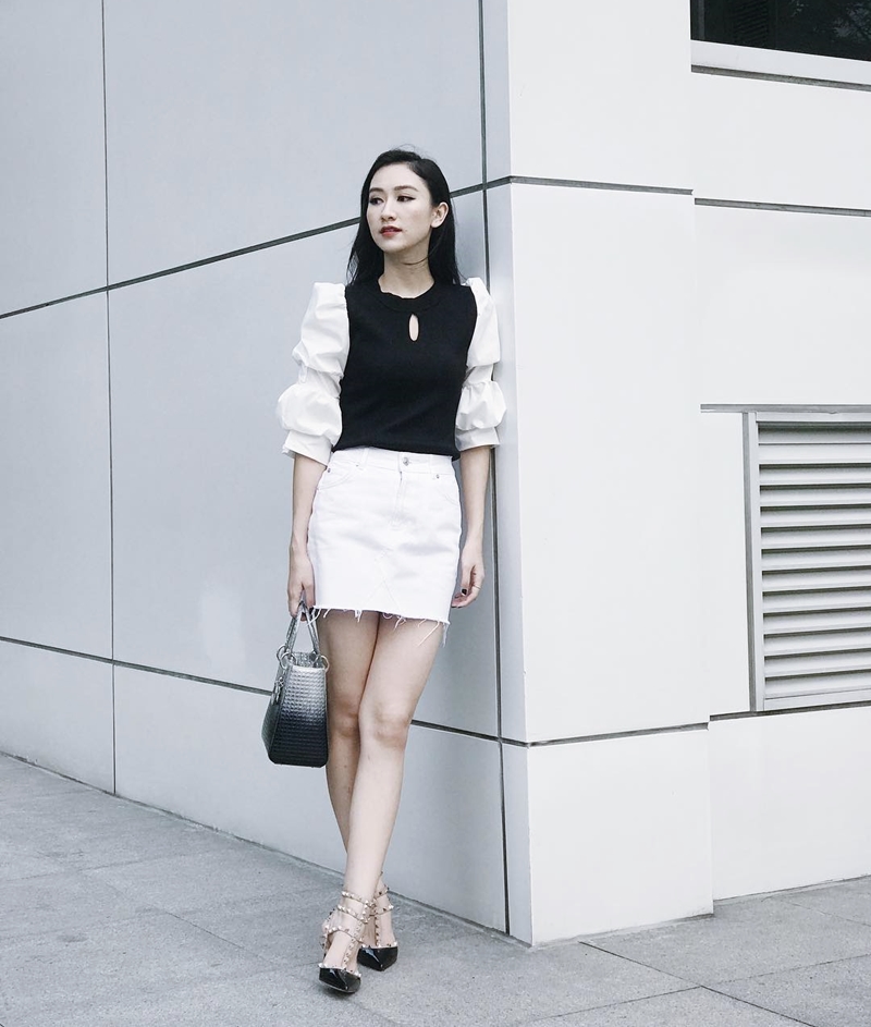 Hà Thu hoá tiểu thư kiêu kỳ với áo blouse tay phồng phối màu đen trắng trang nhã, kết hợp chân váy ngắn và giày cao gót Valentino. Chiếc túi Dior tán sắc độc đáo trở thành phụ kiện hoàn thiện phong cách minimalist, giúp người đẹp toả sắc yêu kiều mà không hề phô trương.  