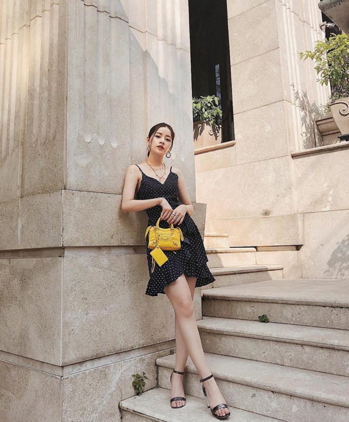 Lựa chọn váy hai dây họa tiết chấm bi cùng góc chụp từ dưới lên, Chi Pu giấu nhẹm khuyết điểm đùi to lại khoe được vòng eo con kiến. Người đẹp khéo léo kết hợp cùng túi Balenciaga màu vàng size mini làm điểm nhấn.    