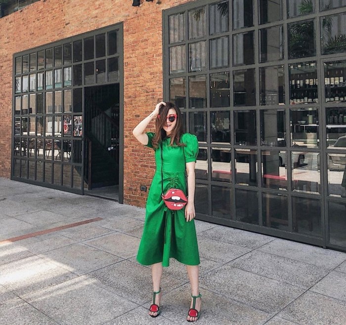 Diện đầm xanh lá tay phồng hơi hướng retro, Yến Nhi khéo tạo điểm chấm phá cho phong cách hoài cổ bằng đôi sandals cao gót gắn hình trái cây và túi đeo hình đôi môi bắt mắt.    
