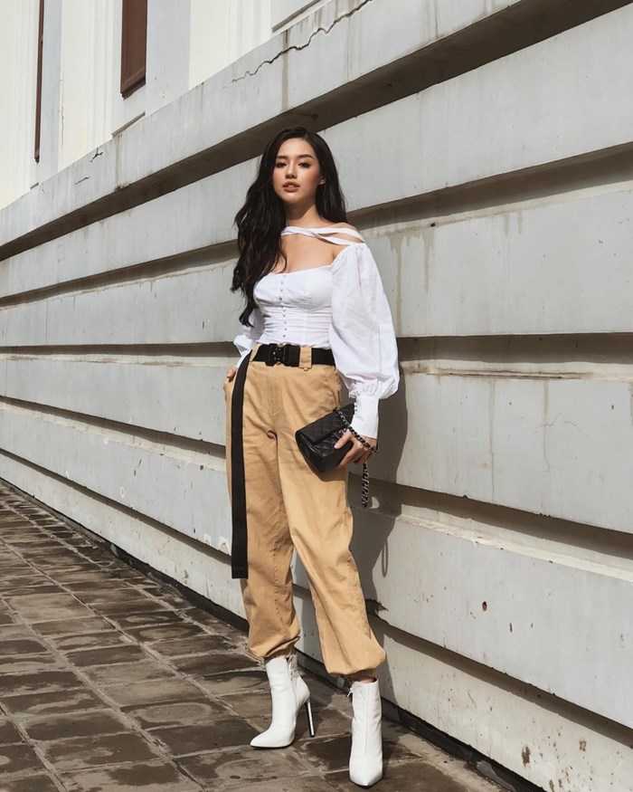 Mùa hè đã dần qua, mẫu áo tay phồng vẫn chưa có dấu hiệu hạ nhiệt. Khánh Linh The Face ghi điểm với cách kết hợp thú vị áo blouse tay phồng có cắt xẻ phần vai lạ mắt. Cô nàng còn phối thiết kế này với quần joggers màu camel, mang boots cao gót và túi Chanel, mix thắt lưng dáng dài cực “chất”.    