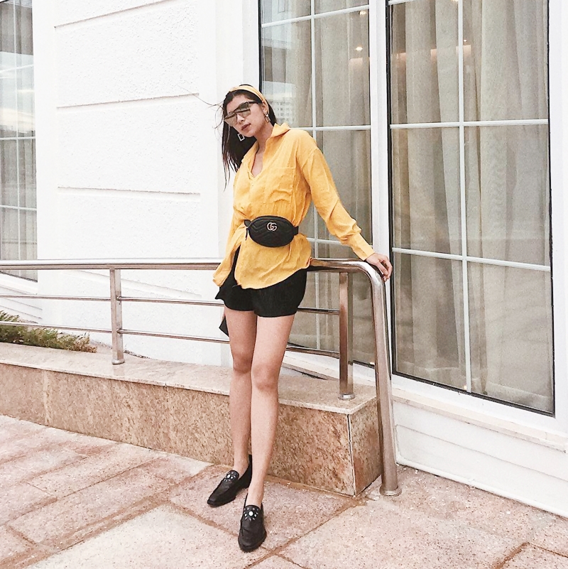 Đồng Anh Quỳnh trổ tài mix đồ sành sỏi khi dùng túi belt của Gucci để tạo điểm thắt eo cho mẫu sơ mi vàng rực, phối cùng quần shorts và giày xỏ ton-sur-ton.    