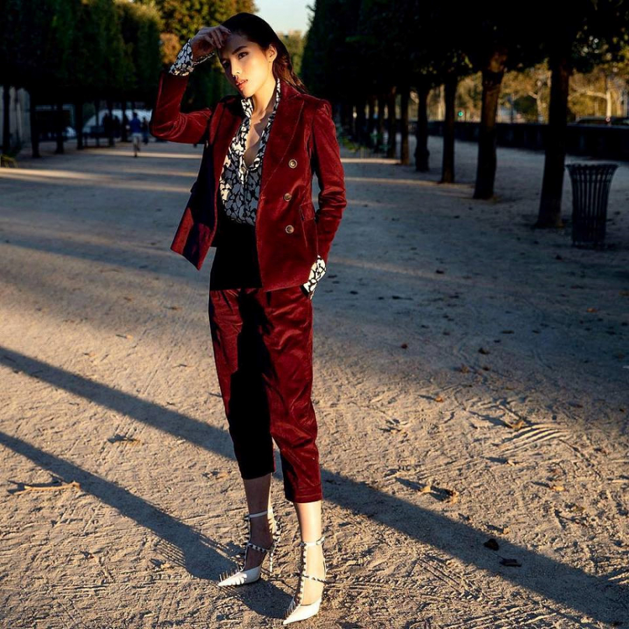 HLV Siêu mẫu Việt Nam 2018 xuất hiện với bộ cánh sắc đỏ nổi bật gồm blazer độn vai và quần ống lửng chất liệu nhung. Bên trong, cô diện áo sơ mi họa tiết cầu kỳ hiệu Saint Laurent. Với set đồ này, người đẹp chọn giày cao gót nạm đinh tán của Balenciaga - thương hiệu thời trang giày đắt đỏ trên thế giới.