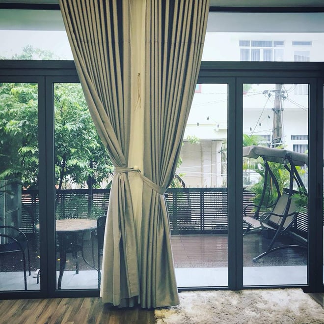 Một mặt căn nhà được thiết kế mở với vách kính ngăn nhìn ra khoảng sân.    