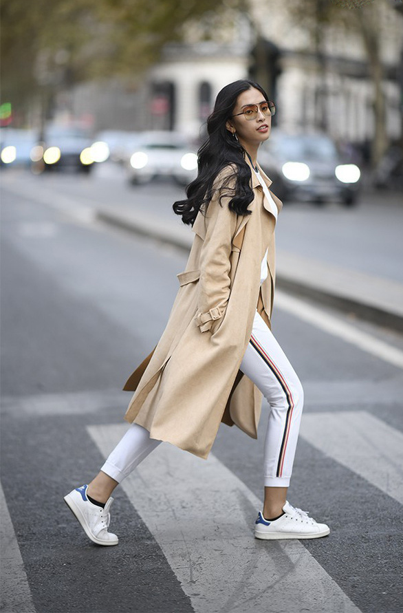 Trong khi cả Hà Tăng và Đỗ Mỹ Linh đều diện blazer kẻ thì riêng một mình HH Tiểu Vy lại chọn trench coat cho street style của mình. Nàng Hậu kết hợp nét thanh lịch của áo khoác dài mix cùng sự khỏe khoắn năng động của một set đồ thể thao trắng. Cao tay hơn cả là thiết kế kính mắt xuyệt tông với trench coat mà cô mặc.    