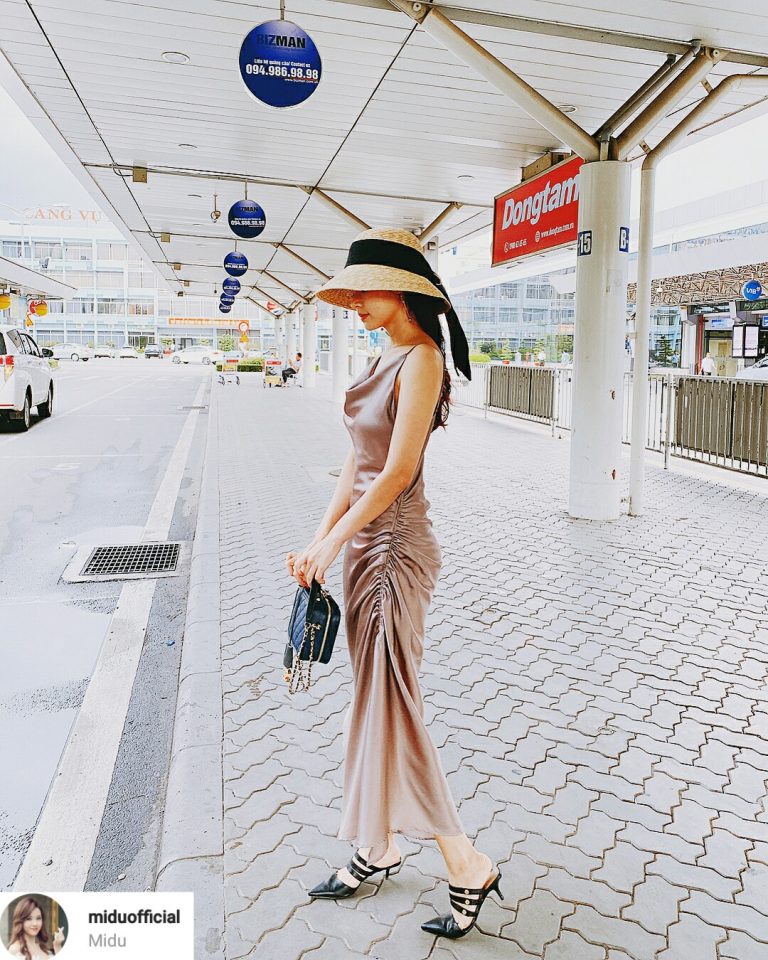 Midu ngọt ngào cùng thiết kế đầm lụa hai dây cổ đổ. Phụ kiện đi kèm có mũ cói dáng chụp đèn, sandals mũi nhọn cùng màu với túi xách hàng hiệu.    