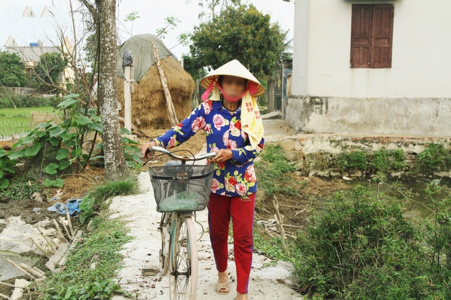 Bà Huệ ủ rũ dắt xe đạp vào nhà sau khi tan phiên chợ chiều.    