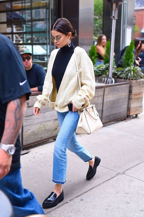 Một chiếc áo thun cổ lọ màu đen, kết hợp với áo khoác len màu sữa đơn giản, quần jeans cùng với giày sleep-on mang đến vẻ năng động và trẻ trung.