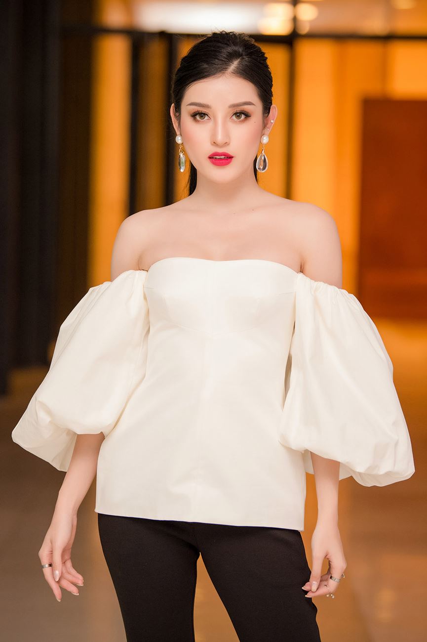 Cô nàng phối áo sơmi trễ vai màu trắng, kết hợp cùng quần đen ống suông cá tính.