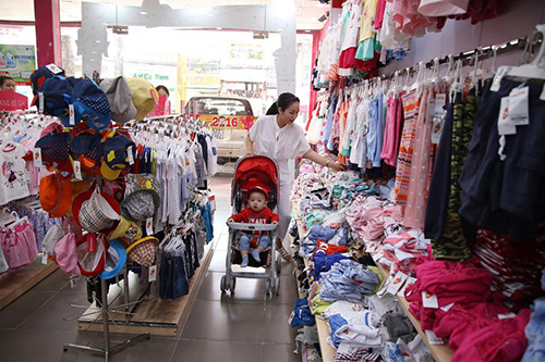 Ốc Thanh Vân rất ra dáng một bà mẹ “bỉm sữa”. Cô ăn vận giản dị, một tay trông con, một tay chọn đồ.    